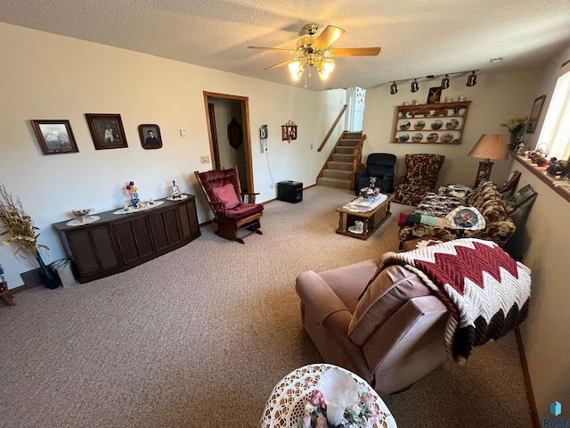 living area with a textured ceiling, carpet floors, stairway, and ceiling fan