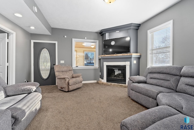 living area with carpet floors, baseboards, and a glass covered fireplace