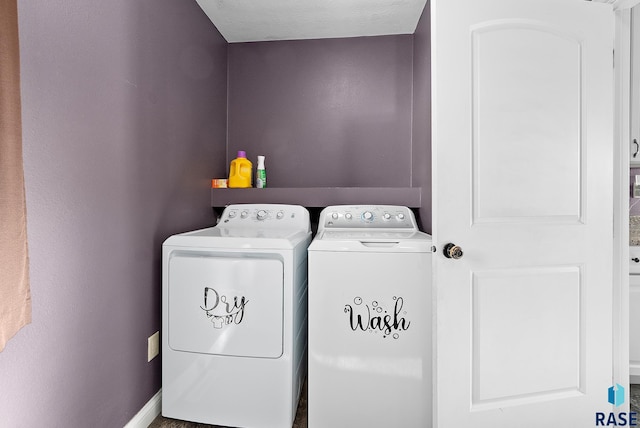 clothes washing area with laundry area, baseboards, and washer and clothes dryer