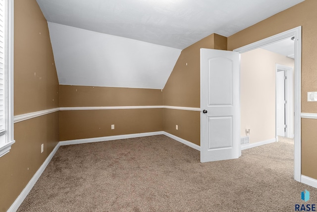 bonus room featuring baseboards, visible vents, vaulted ceiling, and carpet flooring