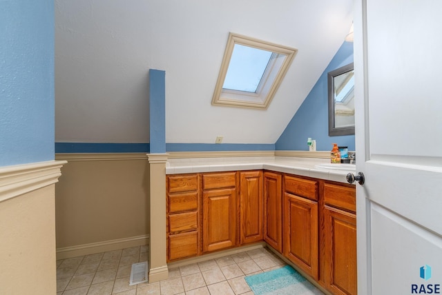 bathroom with vaulted ceiling with skylight, vanity, visible vents, and tile patterned floors