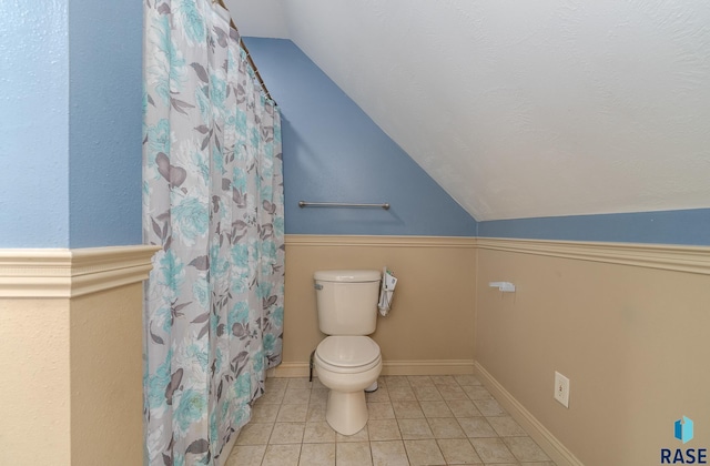 full bathroom featuring baseboards, toilet, a shower with curtain, lofted ceiling, and tile patterned flooring