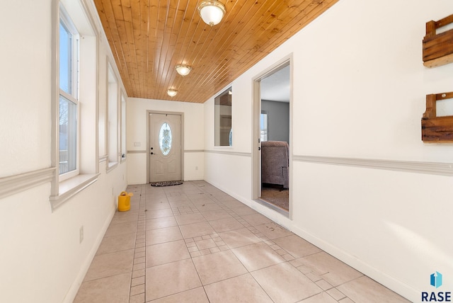 doorway to outside featuring light tile patterned floors, wooden ceiling, and baseboards