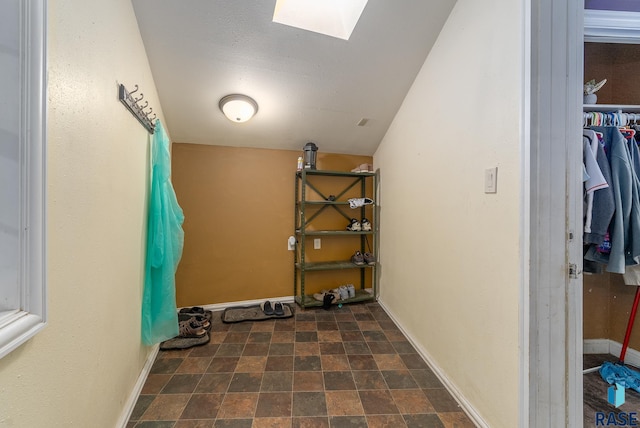 workout area featuring stone finish flooring, a skylight, and baseboards