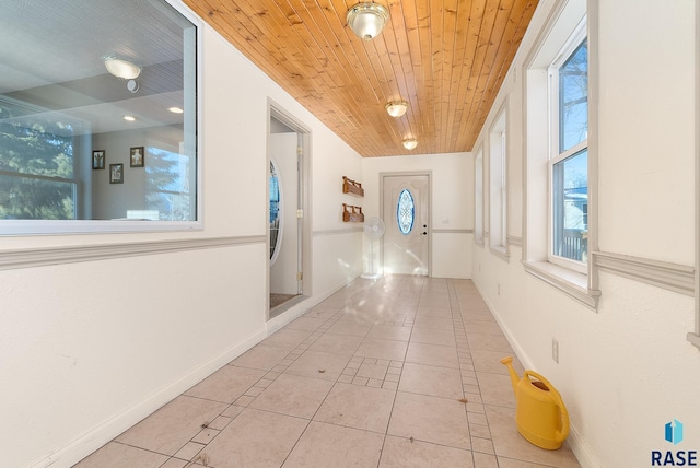 hallway with light tile patterned floors, wooden ceiling, a wealth of natural light, and baseboards