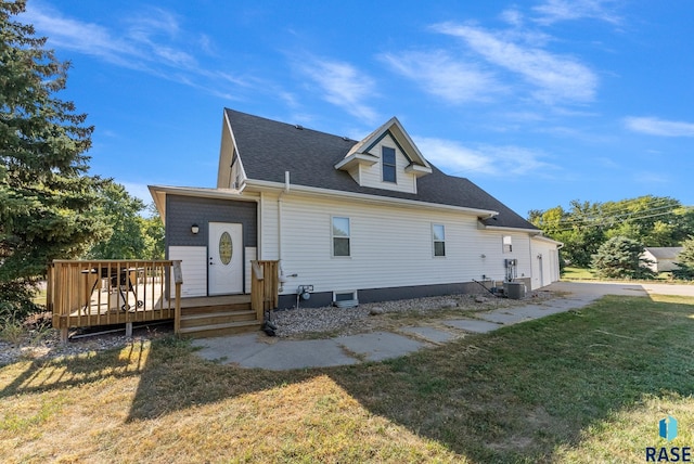 exterior space featuring a shingled roof, central AC unit, a deck, and a front yard