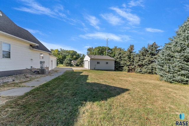 view of yard featuring a garage, central AC unit, and an outdoor structure