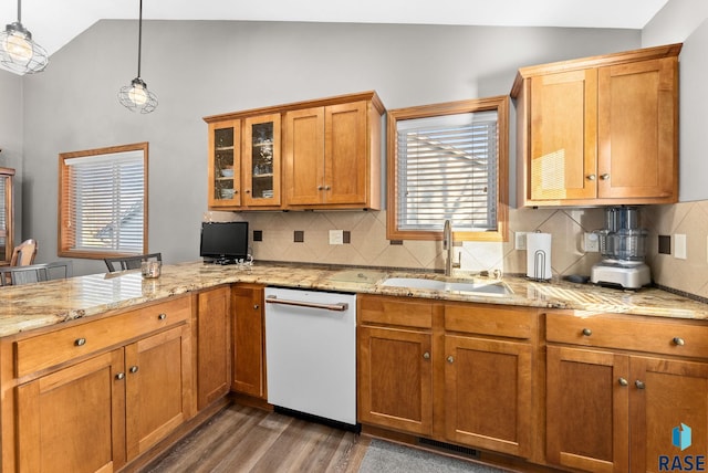 kitchen featuring brown cabinetry, wood finished floors, white dishwasher, vaulted ceiling, and a sink