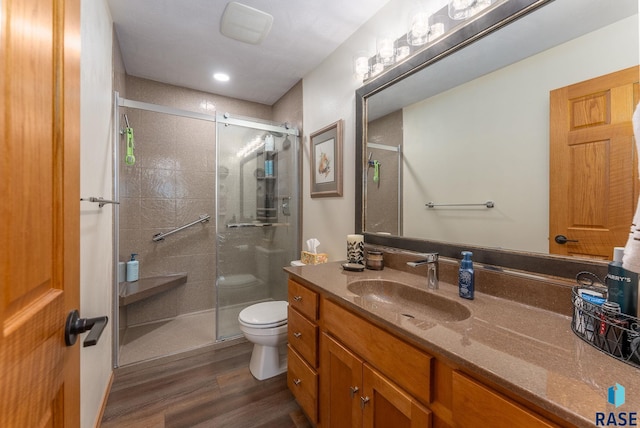 full bath with vanity, a shower stall, toilet, and wood finished floors