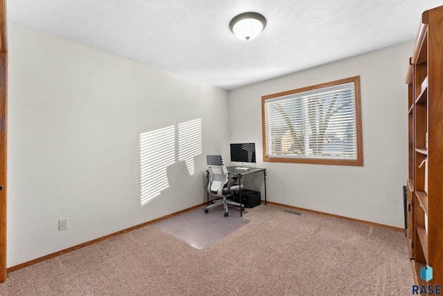 carpeted office featuring visible vents and baseboards