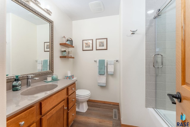 bathroom featuring visible vents, toilet, vanity, wood finished floors, and baseboards