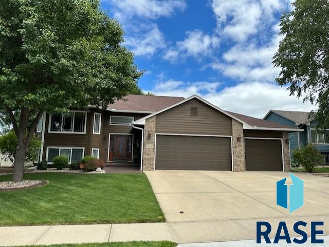 view of front of home featuring an attached garage, driveway, and a front yard