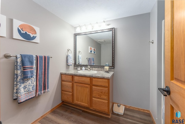 bathroom featuring baseboards, wood finished floors, and vanity