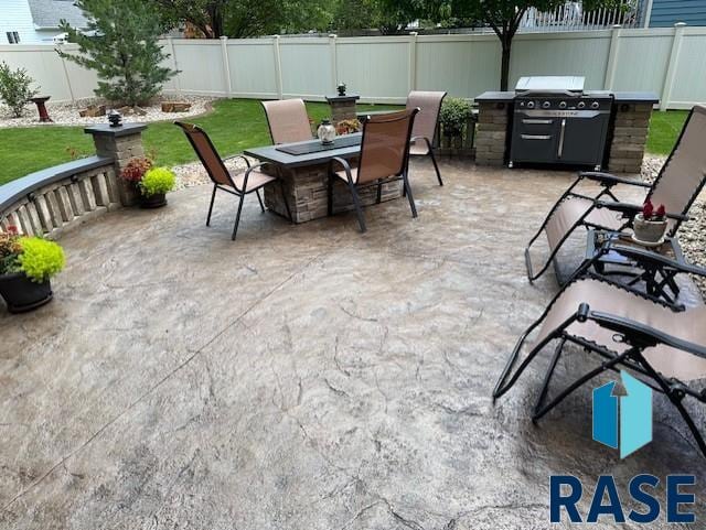 view of patio with a fenced backyard, a fire pit, and grilling area