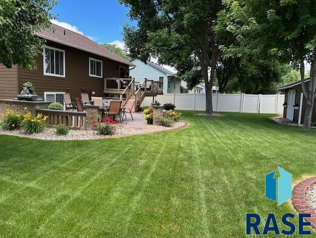 view of yard with a patio area, fence, and a wooden deck