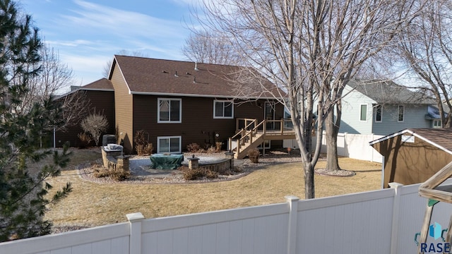 rear view of house with a deck, a fenced backyard, roof with shingles, stairway, and a lawn