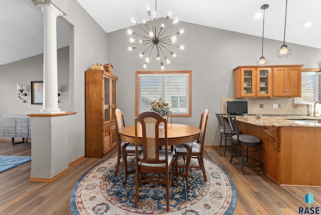 dining area featuring high vaulted ceiling, light wood-style flooring, decorative columns, and baseboards