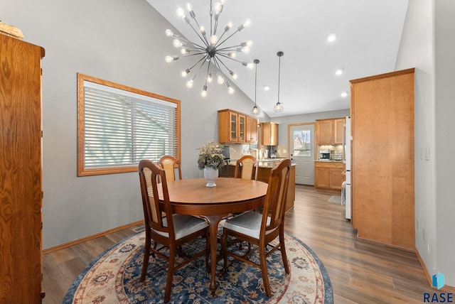 dining space featuring baseboards, wood finished floors, high vaulted ceiling, a notable chandelier, and recessed lighting