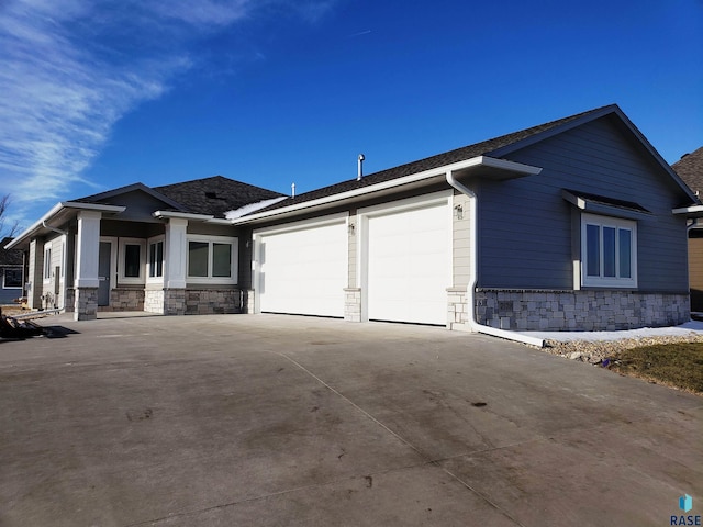 view of front facade with stone siding, an attached garage, and driveway