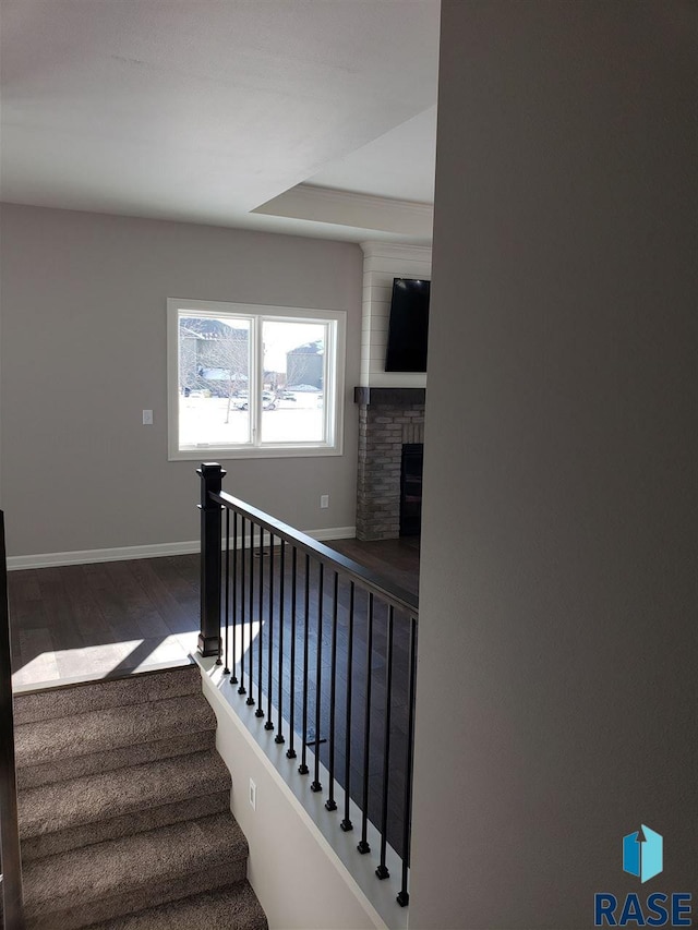 staircase with a fireplace, baseboards, and wood finished floors