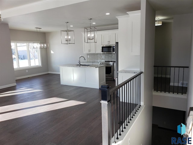 kitchen featuring stainless steel appliances, dark wood-style flooring, a sink, baseboards, and decorative backsplash