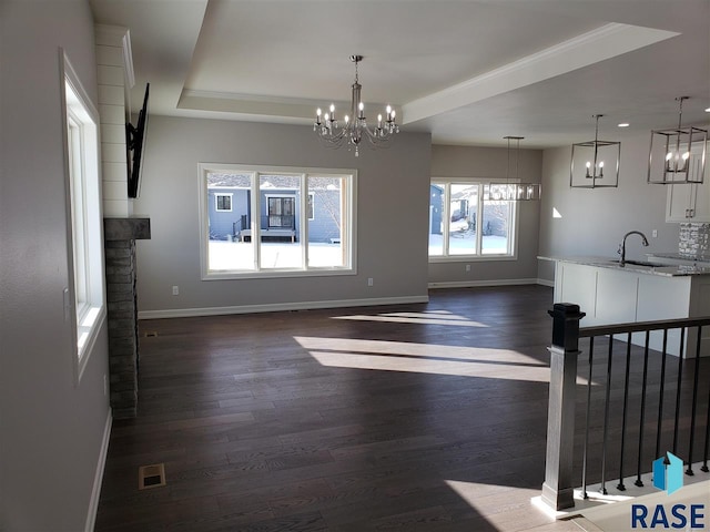 unfurnished dining area featuring a sink, baseboards, a raised ceiling, and dark wood-style flooring