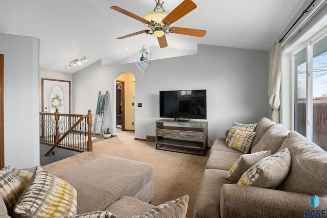 living room with arched walkways, baseboards, ceiling fan, carpet, and vaulted ceiling