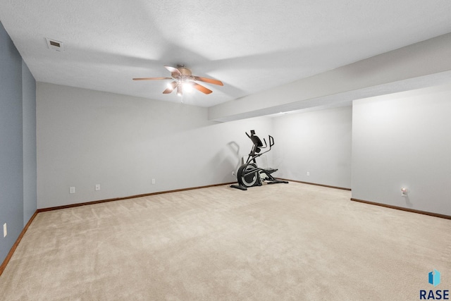 exercise area with baseboards, a textured ceiling, visible vents, and carpet flooring