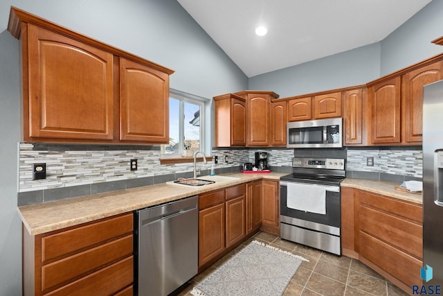 kitchen with backsplash, appliances with stainless steel finishes, vaulted ceiling, and a sink