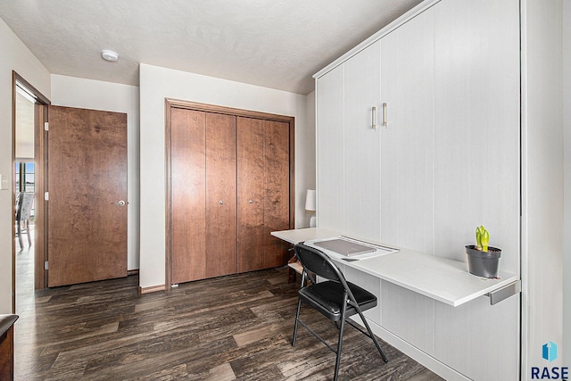 home office featuring a textured ceiling, dark wood-style floors, and built in study area