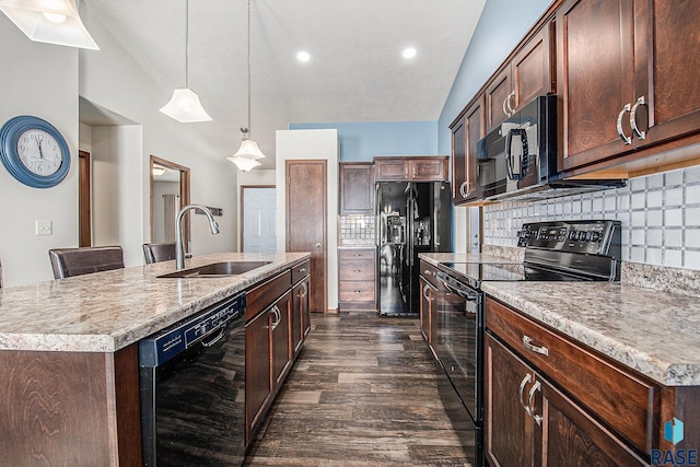 kitchen with a sink, decorative backsplash, black appliances, and an island with sink