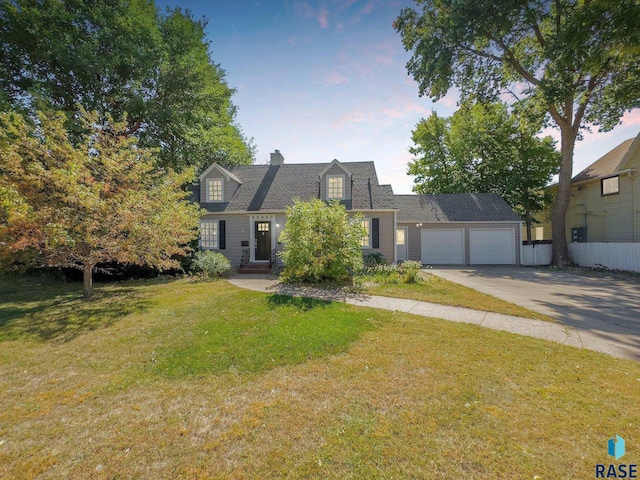 cape cod-style house featuring a yard, a chimney, fence, a garage, and driveway