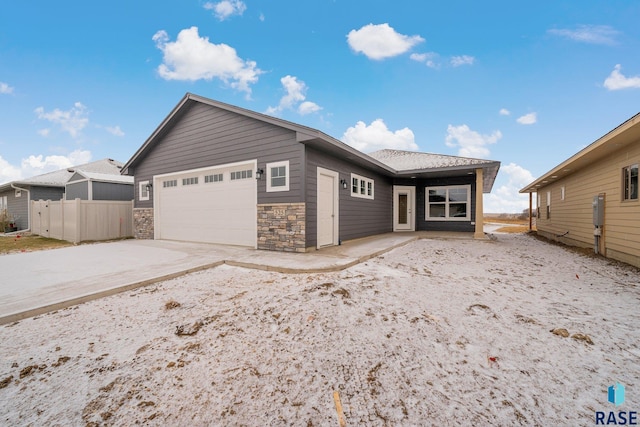 single story home with an attached garage, stone siding, fence, and concrete driveway