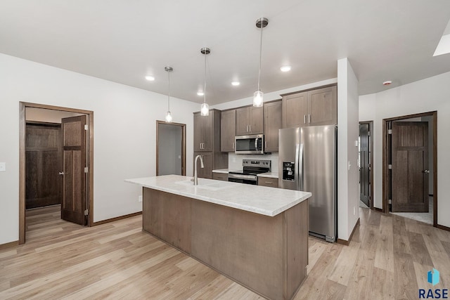 kitchen with stainless steel appliances, light countertops, light wood-style floors, a sink, and dark brown cabinets