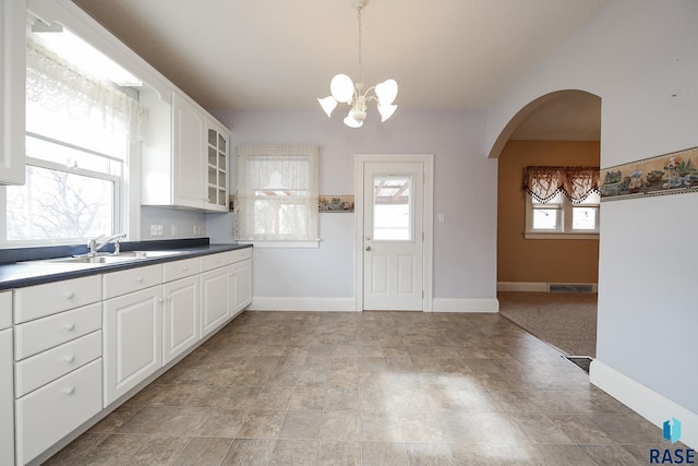 kitchen featuring glass insert cabinets, arched walkways, a healthy amount of sunlight, and white cabinets