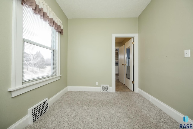 carpeted empty room with baseboards and visible vents