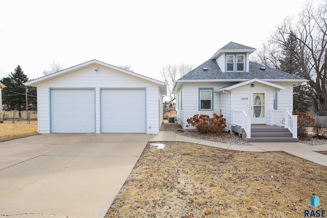 view of front of house featuring an outbuilding, a shingled roof, and a detached garage