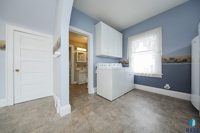 laundry room featuring washer and dryer, cabinet space, and baseboards