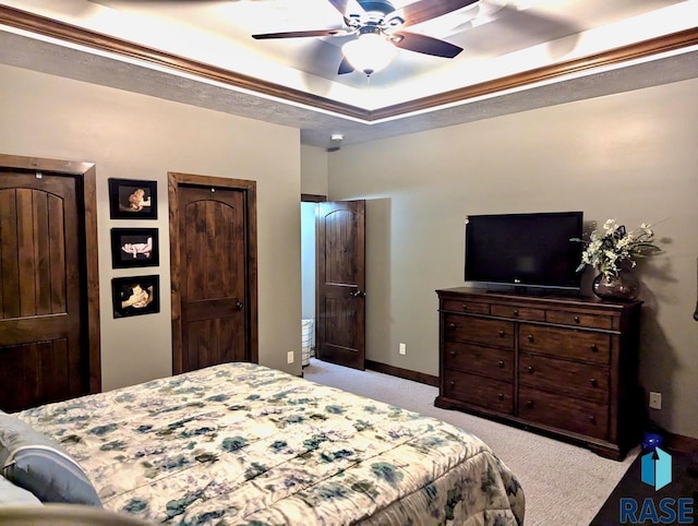 bedroom with baseboards, a raised ceiling, a ceiling fan, and light colored carpet