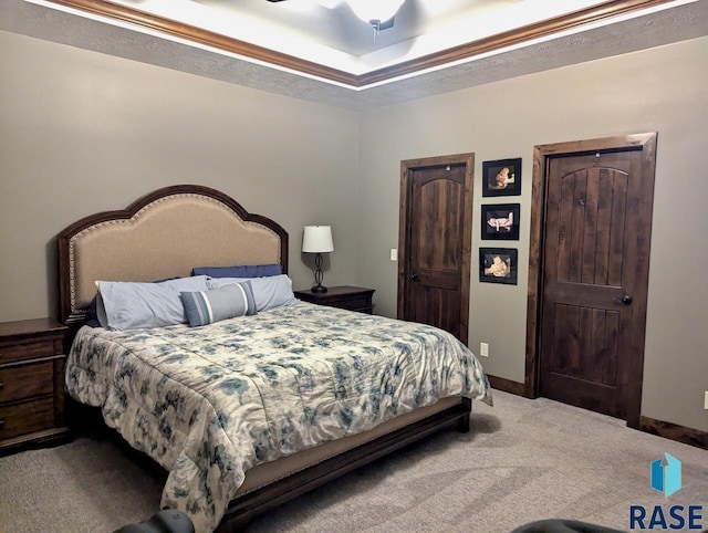 carpeted bedroom featuring a tray ceiling and baseboards