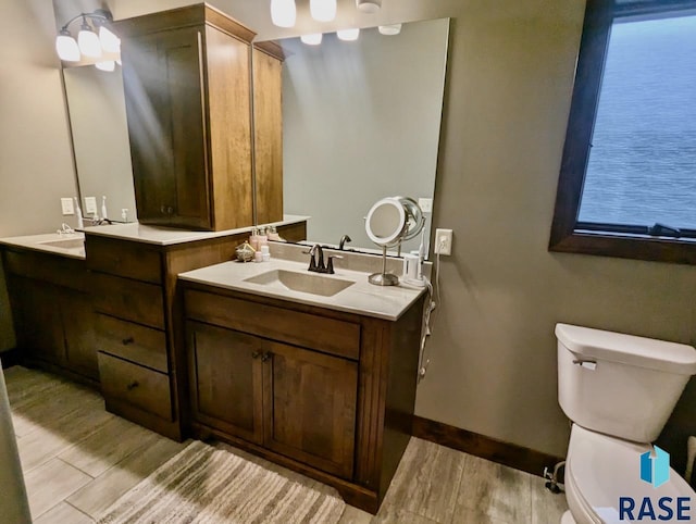 full bath featuring wood finished floors, vanity, toilet, and baseboards