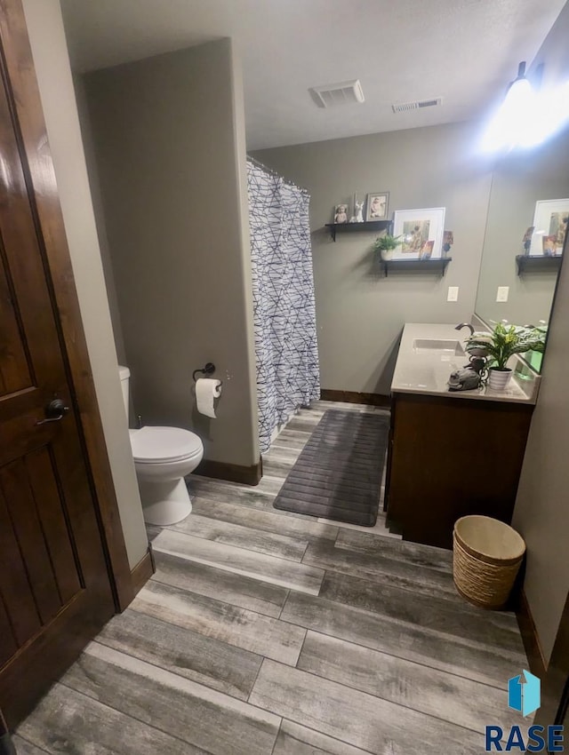 bathroom featuring toilet, wood tiled floor, visible vents, and vanity