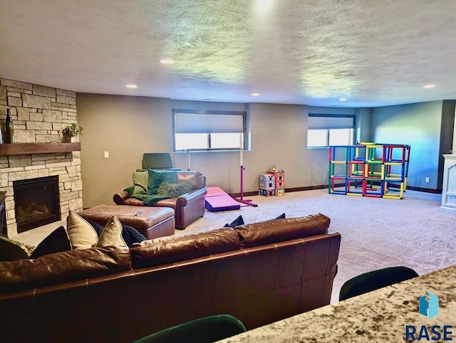 carpeted living area featuring recessed lighting, baseboards, a textured ceiling, and a stone fireplace