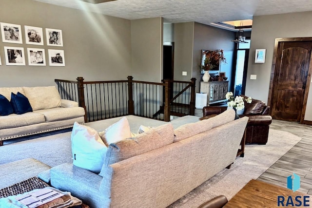 living area featuring an inviting chandelier, a textured ceiling, and wood finished floors