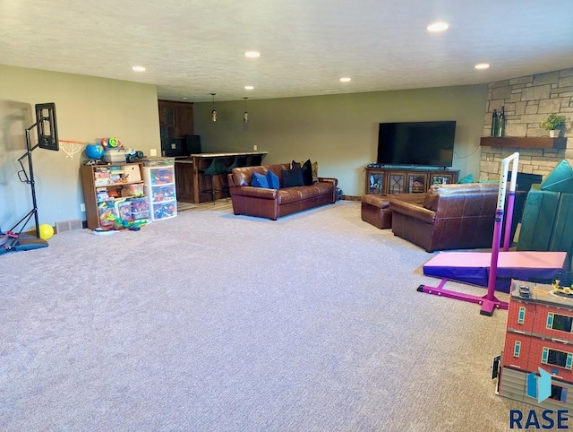 carpeted living room featuring visible vents, a textured ceiling, a bar, a fireplace, and recessed lighting