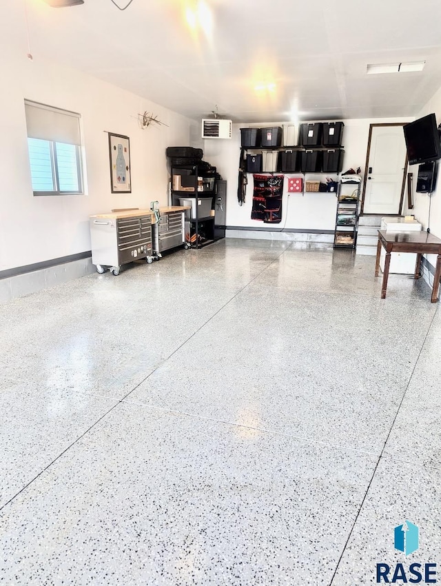 garage with a wall unit AC and baseboards