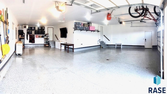 garage with baseboards, a garage door opener, and a wall mounted AC