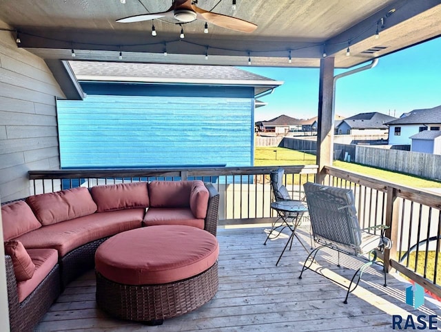 wooden terrace featuring a ceiling fan, a residential view, fence, and an outdoor living space