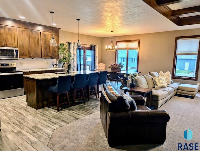 living area featuring a textured ceiling, light wood finished floors, and an inviting chandelier