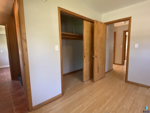 unfurnished bedroom featuring light wood-style flooring, baseboards, and a closet